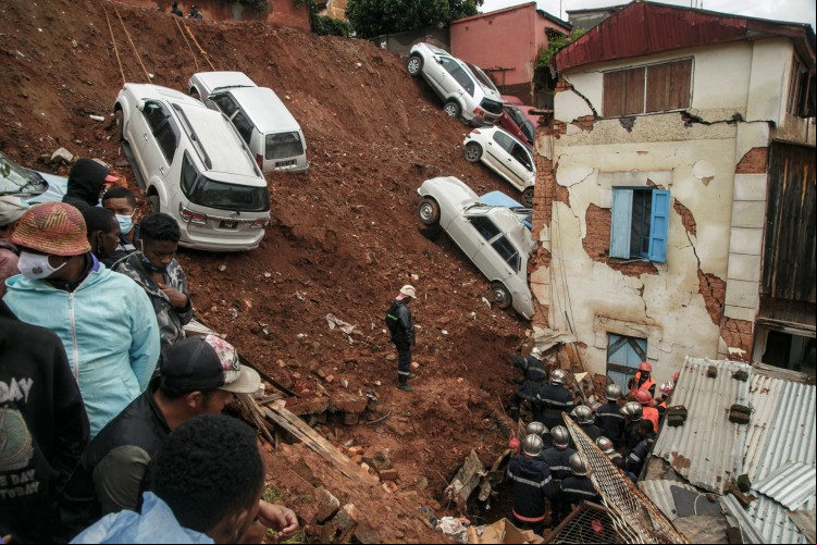 Bombeiros vasculham escombros depois que um estacionamento que abrigava vários carros particulares desabou em casas após as fortes chuvas dos últimos dias no bairro Ankadifotsy de Antananarivo em 24 de janeiro de 2022