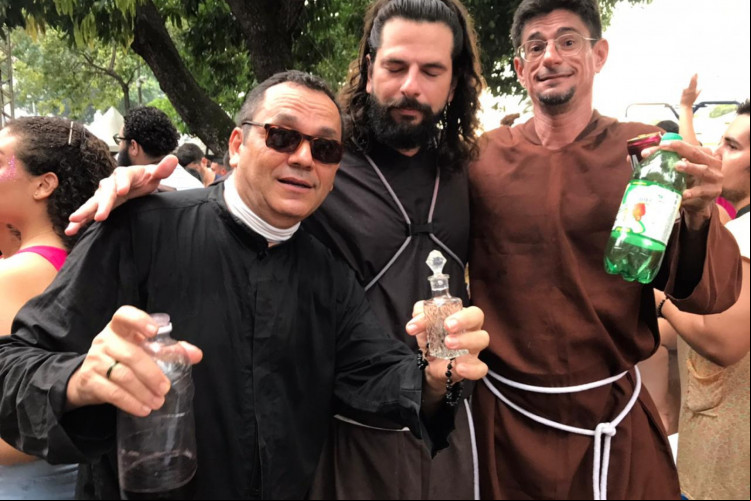 Um casal e um amigo fantasiados de padres católicos, na Praça João Gentil.