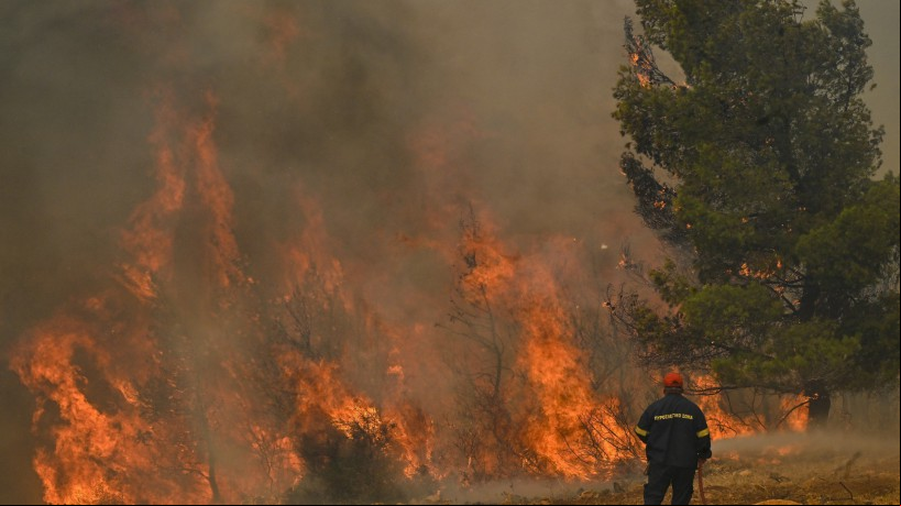 Bombeiro diante de incêndio florestal próximo a Atenas, na Grécia, durante onda de calor
