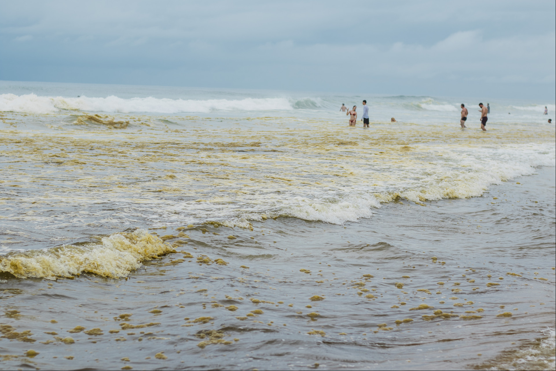 Na foto, banhistas visitam a Praia do Futuro e dão um mergulho, mesmo com o mar apresentando outra tonalidade