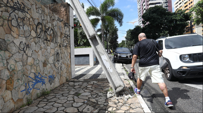 Poste inclinado afeta agem de transeuntes na calçada, na avenida Senador Virgílio Távora, no bairro Aldeota, em Fortaleza